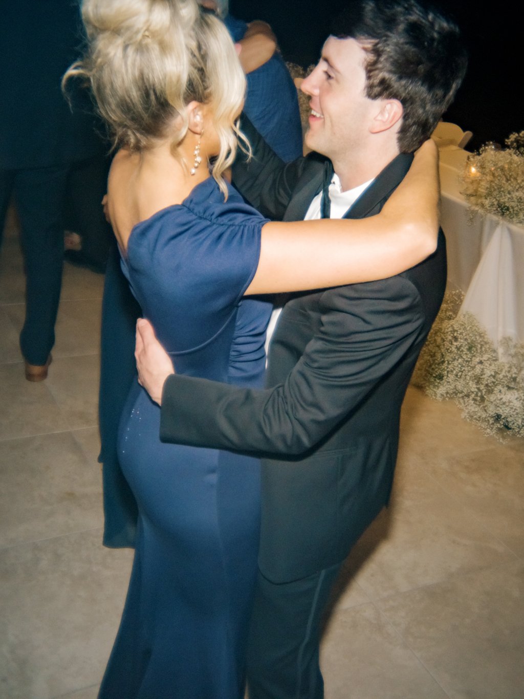 A man and a woman dancing closely at a celebration or event, smiling at each other.