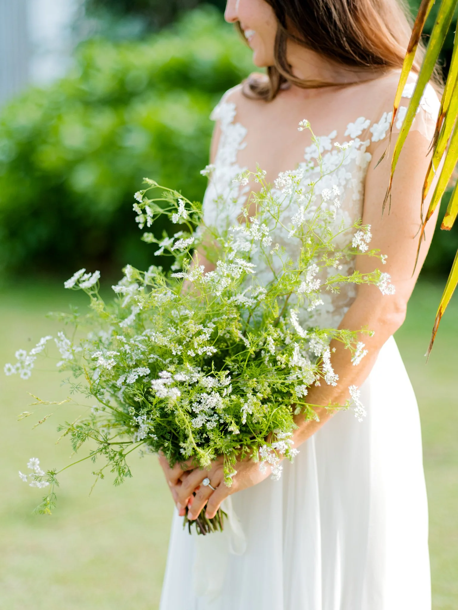A woman in a white dress holding a bouquet of wildflowers outdoors at The Other Side Hotel Eleuthera during a luxury Bahamas destination wedding.