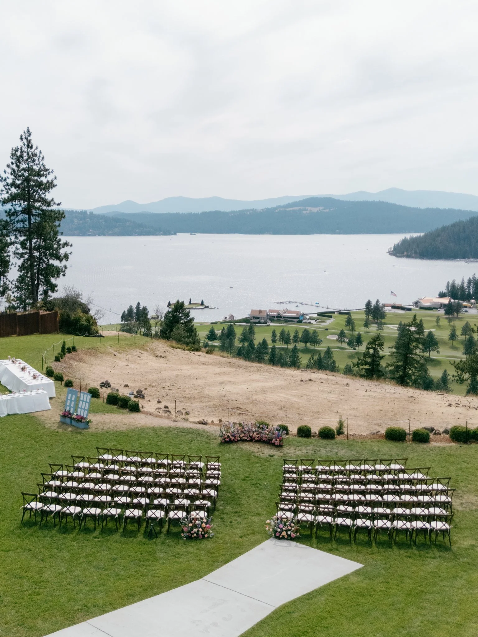 Outdoor wedding ceremony setup with rows of chairs decorated with flowers, overlooking a lake and mountain landscape in Coeur d'Alene, Idaho.