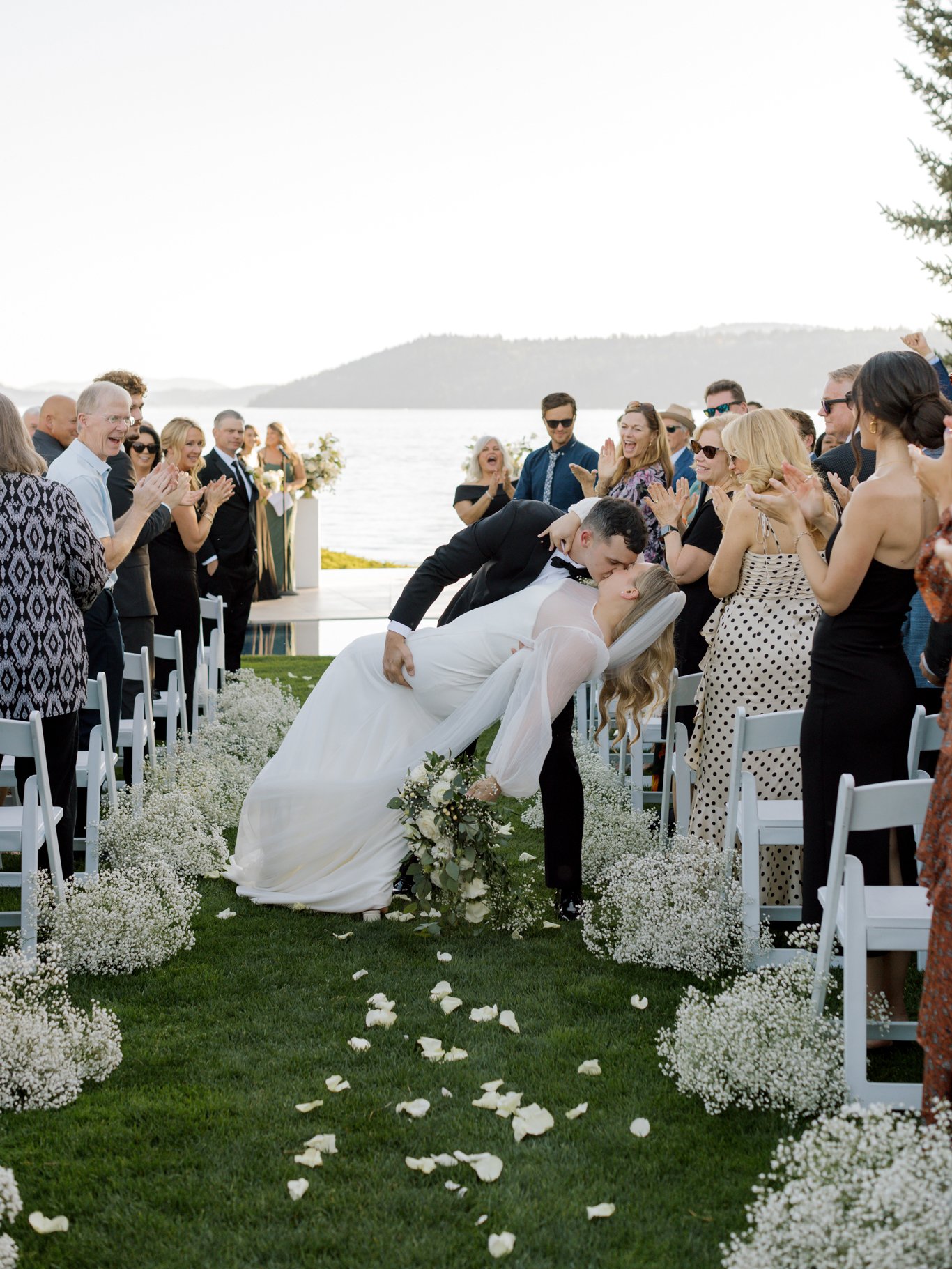 Guests applaud as the bride and groom celebrate down the aisle after their ceremony at the Hagadone Event Center