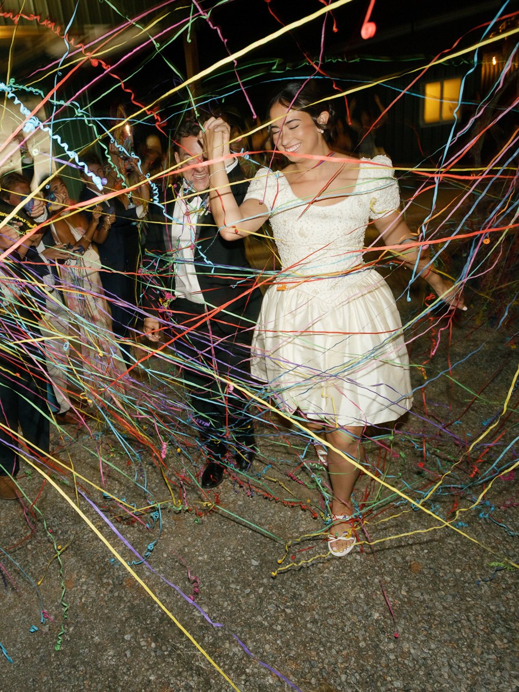 People celebrating at a party with colorful streamers, dancing and smiling.