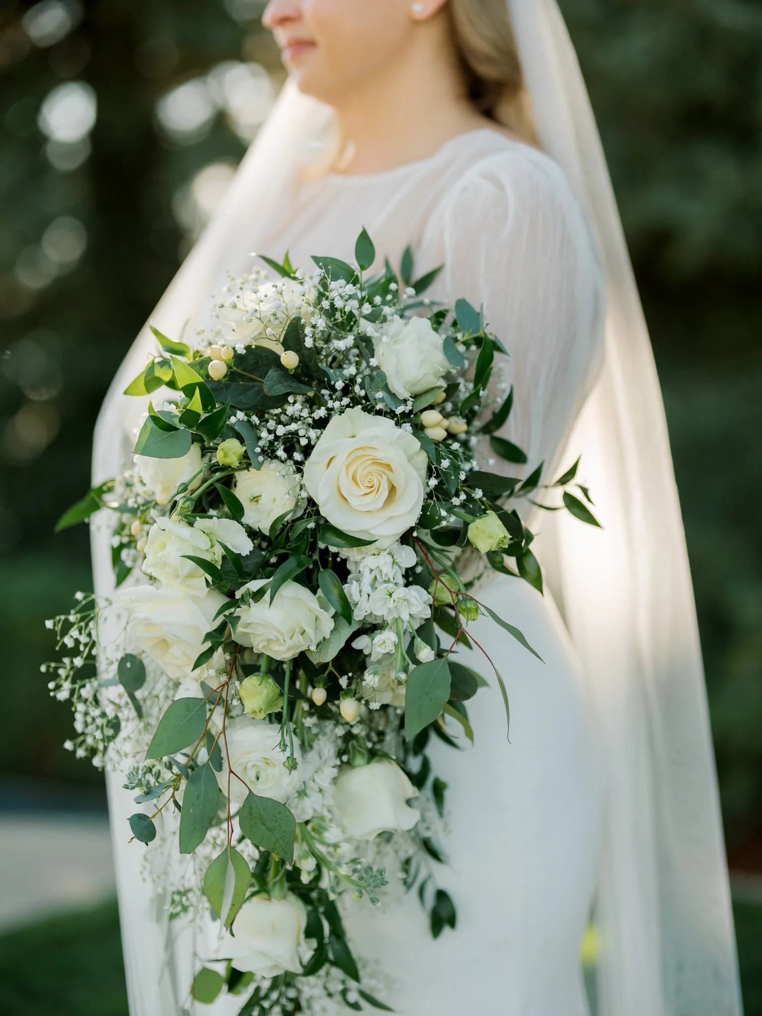 Detail photo of the bride’s cascading bouquet featuring white roses, greenery, and delicate florals during a summer wedding in Coeur d’Alene.