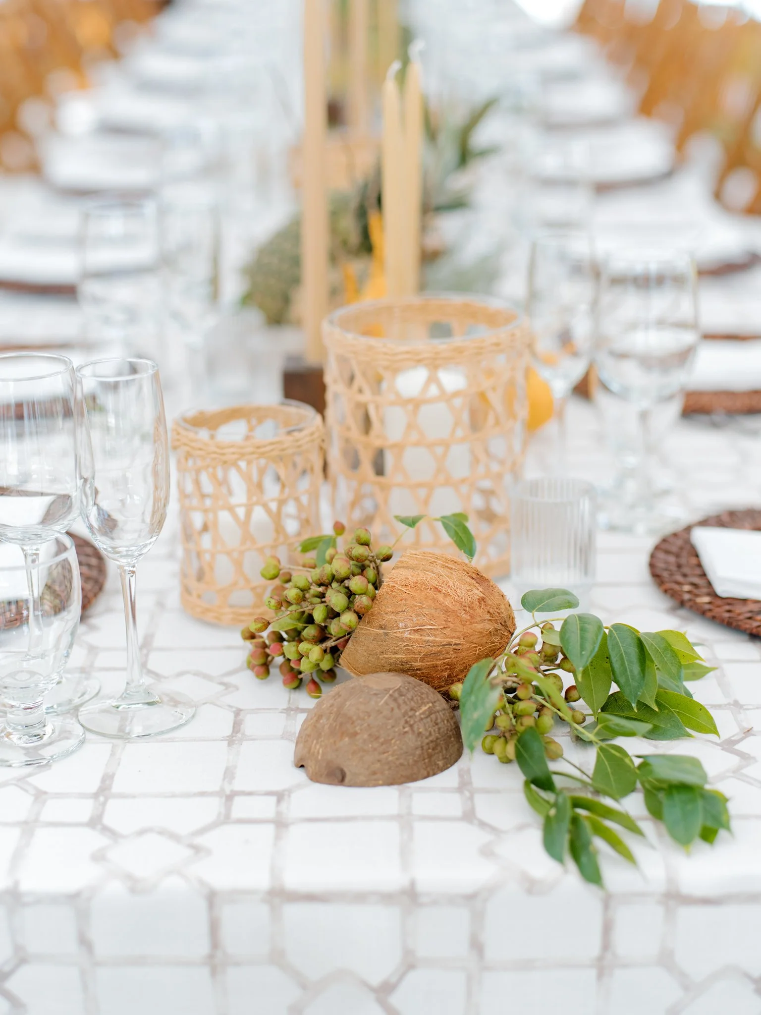 Decorated dining table with candles, greenery, coconuts, and glassware at a rustic outdoor event at The Other Side Hotel Eleuthera during a luxury Bahamas destination wedding.
