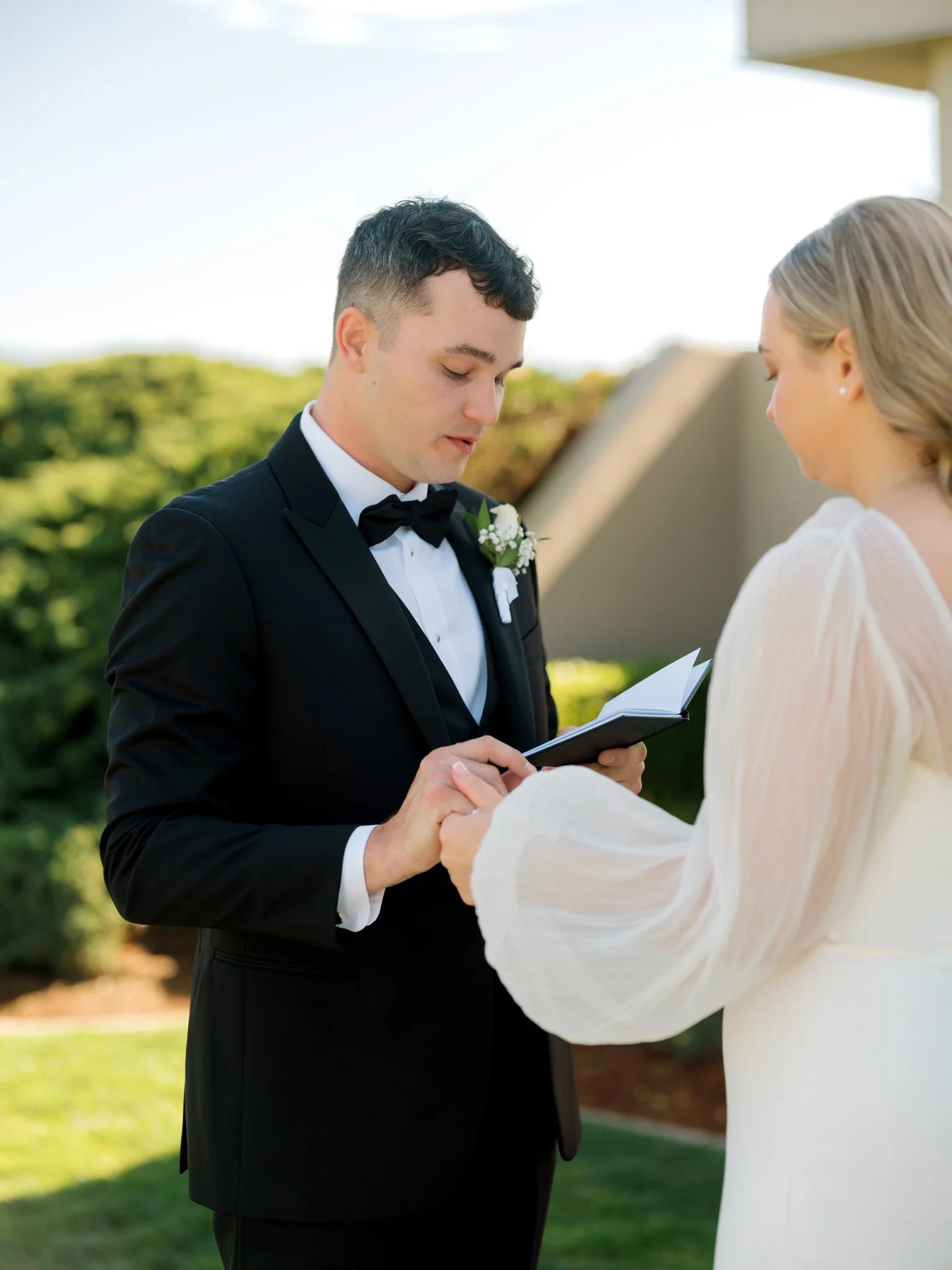 Groom reading handwritten vows to the bride during an intimate pre-ceremony moment outside the Hagadone Event Center.