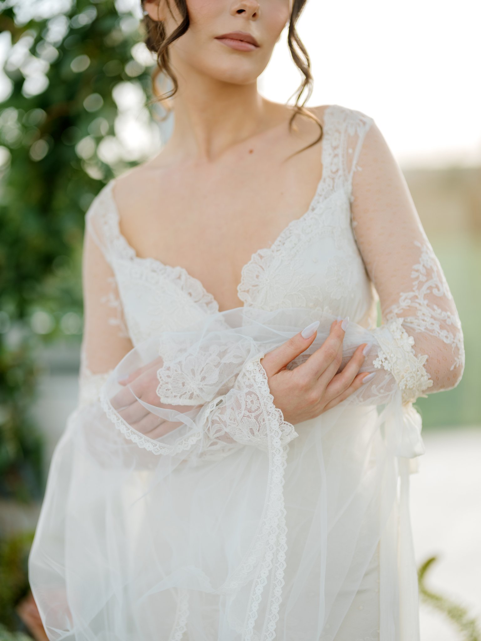 Close-up of a woman in a lace wedding dress holding her hand over her chest outdoors at Greenhouse on Harvard near Spokane, Washington