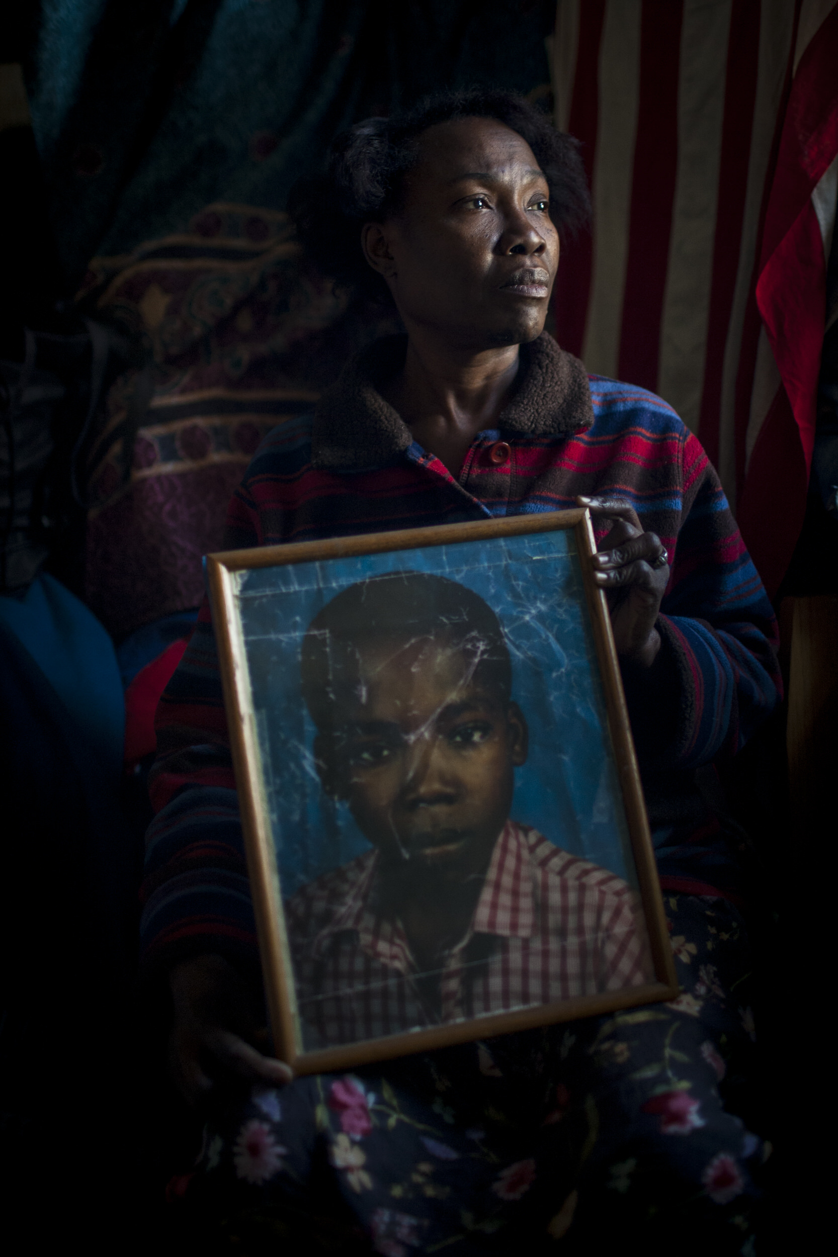  A woman holds a photo of her missing son, later found safe, following a devastating earthquake in Haiti. Brooklyn, NY  