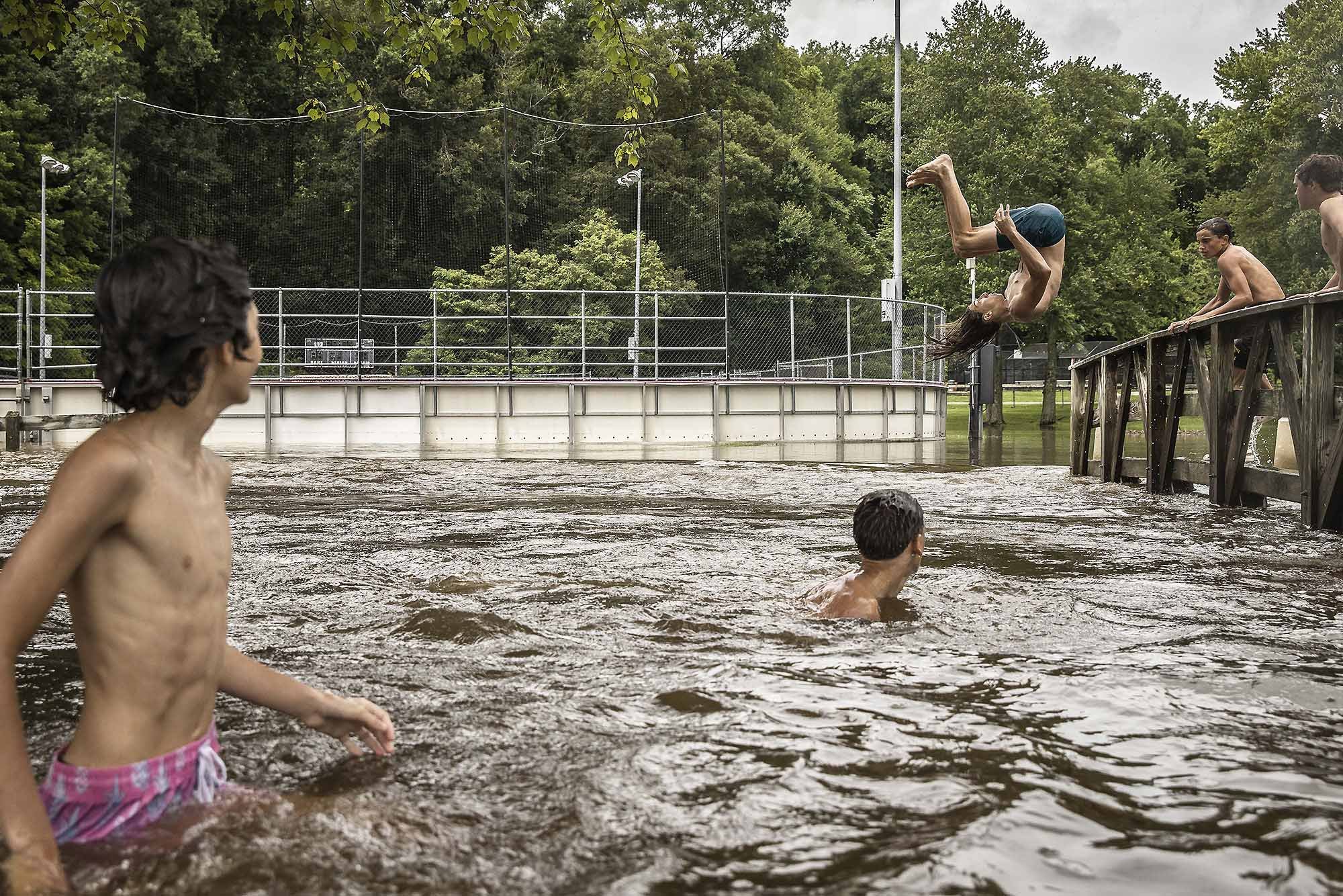  Friends jump into a creek normally two feet deep after a storm resulted in flash-flooding across the Hudson Valley. Shrub Oak, NY.  