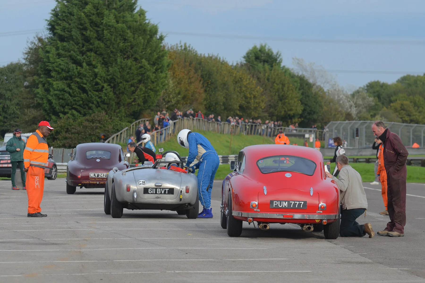 In the foreground Paul Chase-Gardner awaits release as Mandie Hadfield walks back from the pitwall in readiness for the arrival of the Elva Courier. Tim Shepherd straps his Dad, Andy, in to the Ace, whilst furthest away David Reed gives encouragement to daughter Hanna, whilst Mum, Anne (far left) looks on. Photo - Ollie Read