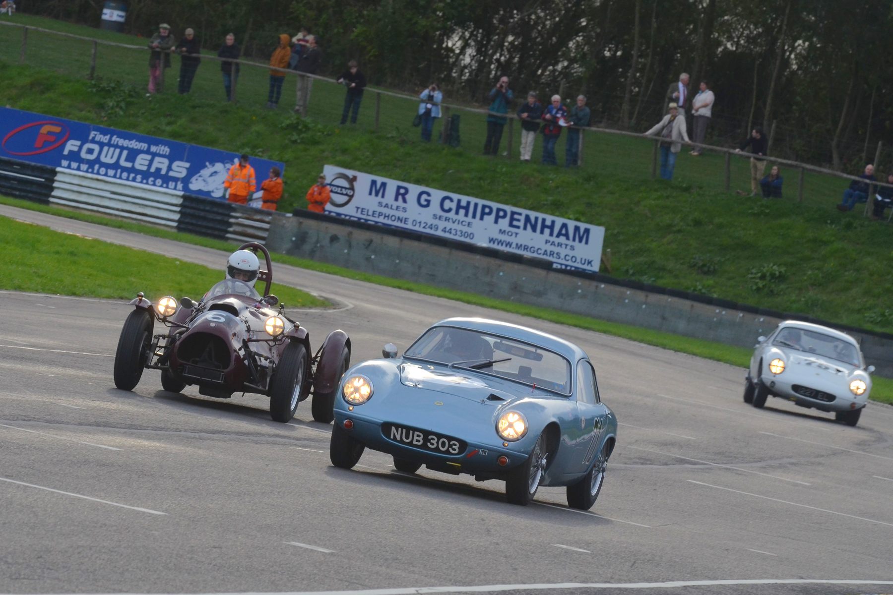 Lights on in the low Autumn sunshine for the 3 front runners as John Ure draws alongside Brian Arculus. The winning car closes in on both, as they exit Camp Corner and head down passed the start/finish line and onto Folly. Photo - Ollie Read 