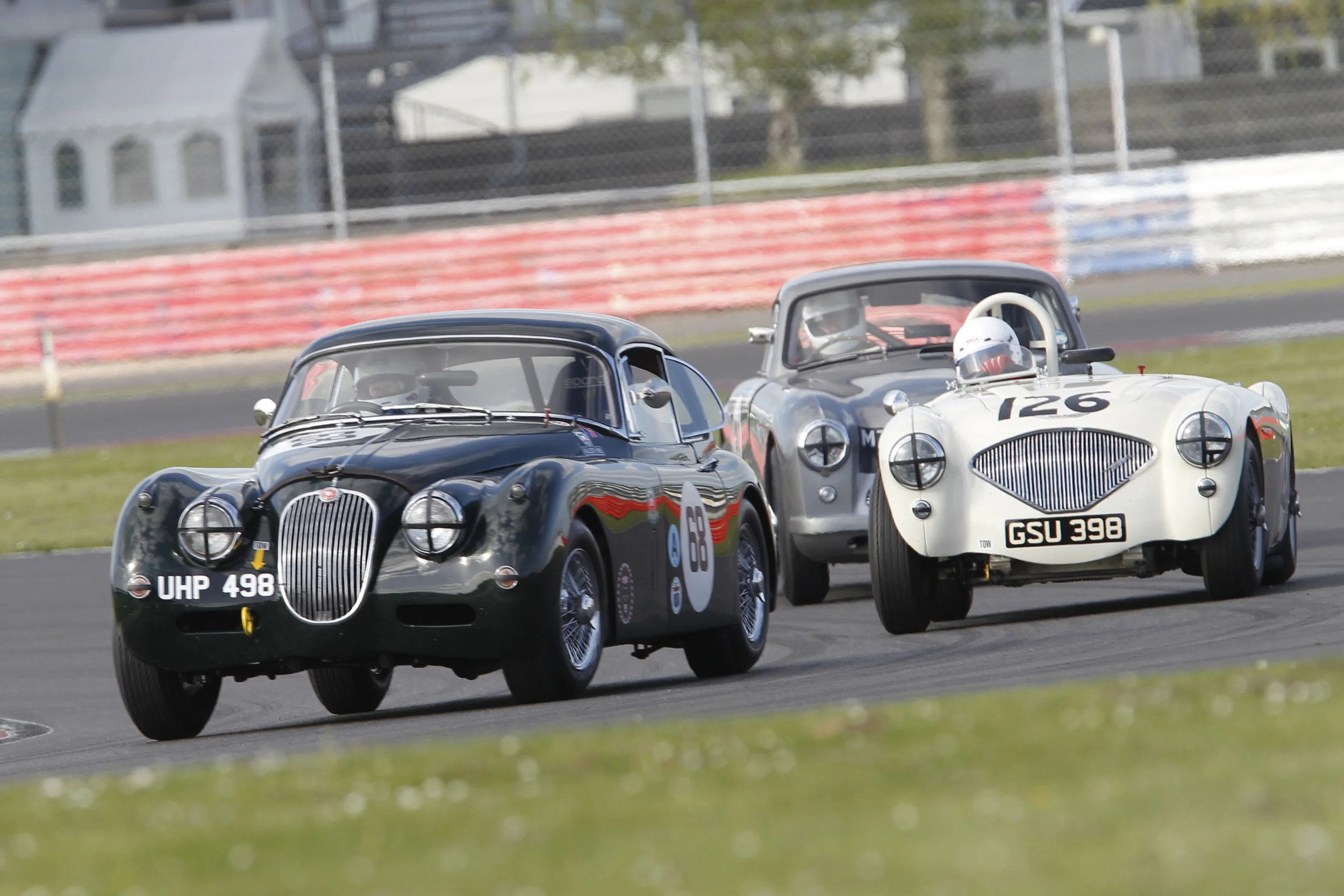 Classic 1950s Marques battle it out on the Silverstone GP Circuit. Marc Gordon (XK150), Nigel Grice (Austin Healey 100) and Tim Stamper (Aston Martin DB2/4) Photo - Mick Wa;lker