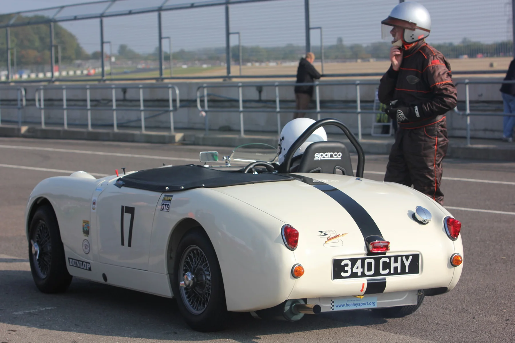 Allan Cameron loosens his helmet, as son Neil prepares to take the Sprite Mk 1 out. They were to finish a fine 18th and 2nd in class Photo - Pat Arculus, Tripos Media