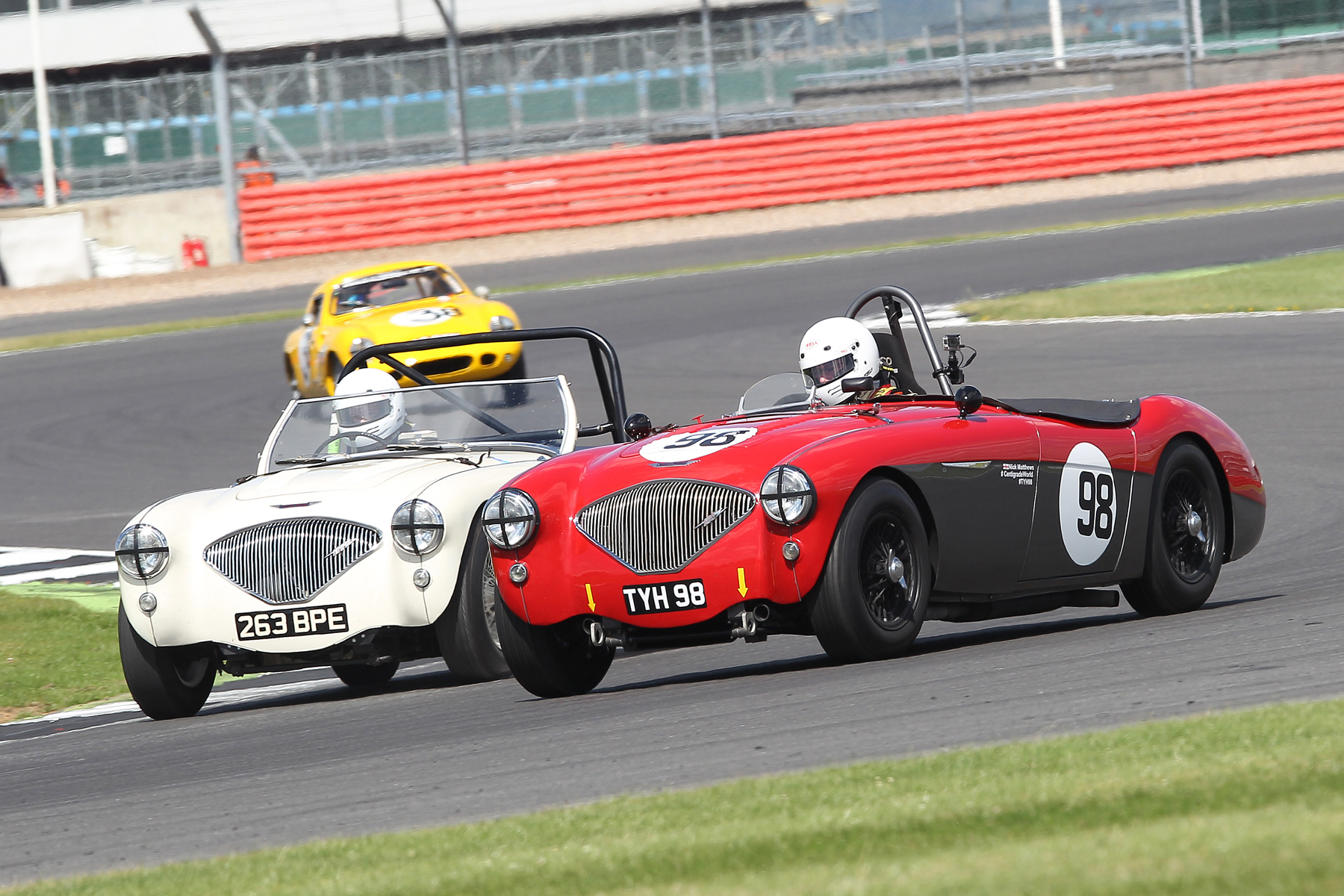 Nick Matthews, a serious and quick club racer with his aero screened Austin Healey 100/4, complete with on board camera, laps the 100M of Matthew Collings, who has been racing his less developed car with standard full width screen for years and just loves being out there. They both had great dices this year. Terrific stuff from both of them. Photo - Mick Walker