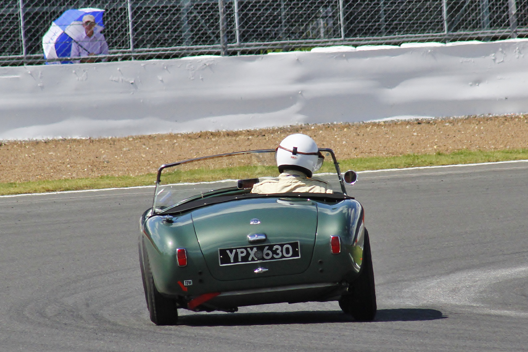 David Bennett about to head through Woodcote. The solitary spectator with sun shade at this point adds a certain artistic posterlike quality Photo - Bob Bull, Tripos Media