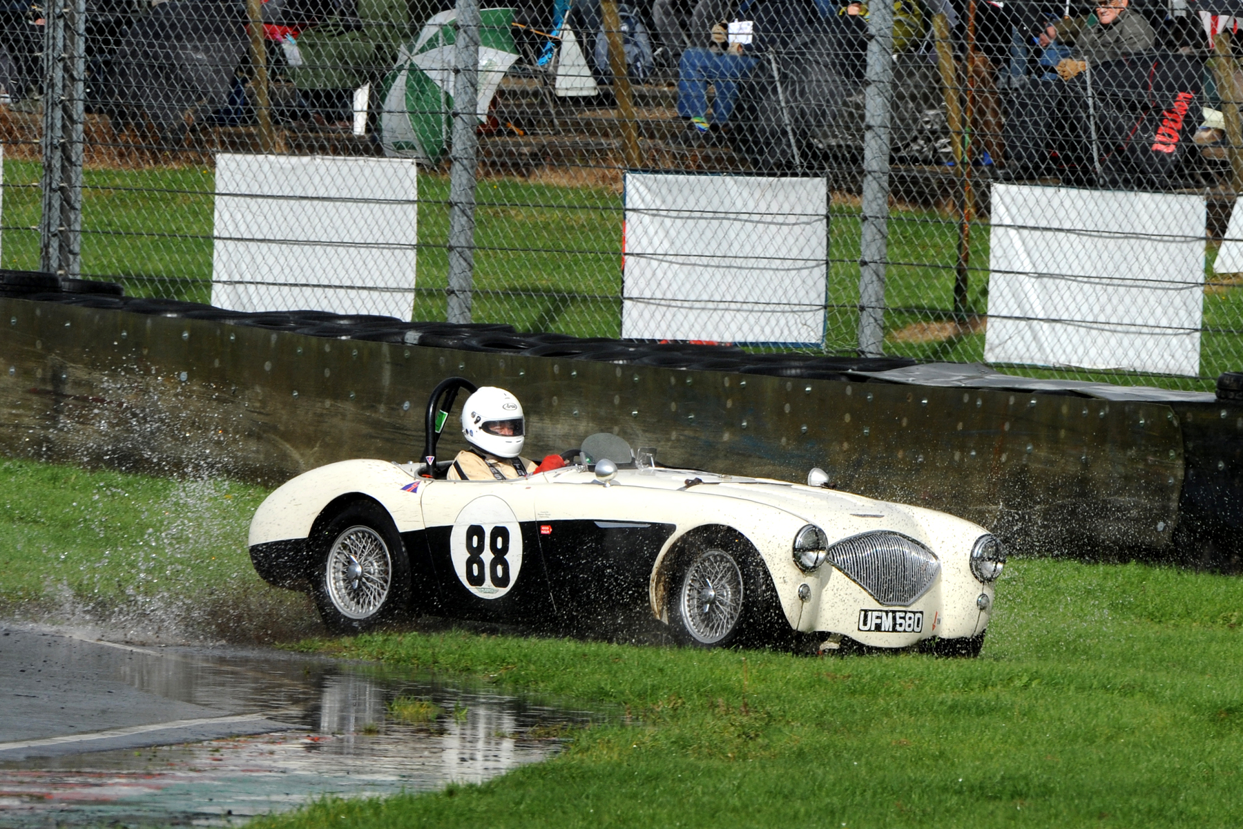 Into Quarry, braking too late, Jeremy Holden sensibly lets his Austin Healey run onto the grass. He returned safely to the track. I think this may be on his out lap following his pit stop when the brakes had cooled. Photo Jeff Bloxham