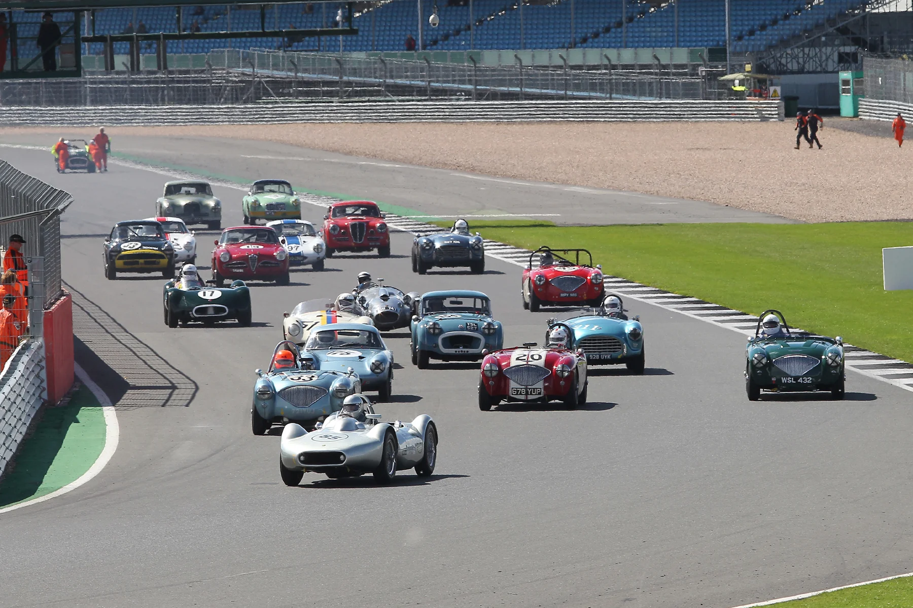 Stephen Bond makes a great get away in the Lister Bristol whilst poleman, Jonathan Abecassis, drops back to 3rd challenged by both Jim Campbell and Robin Ellis. In the background, Mark Hoble's TR2 is about to be pushed off the track after failing to get off the line. Photo - Mick Walker