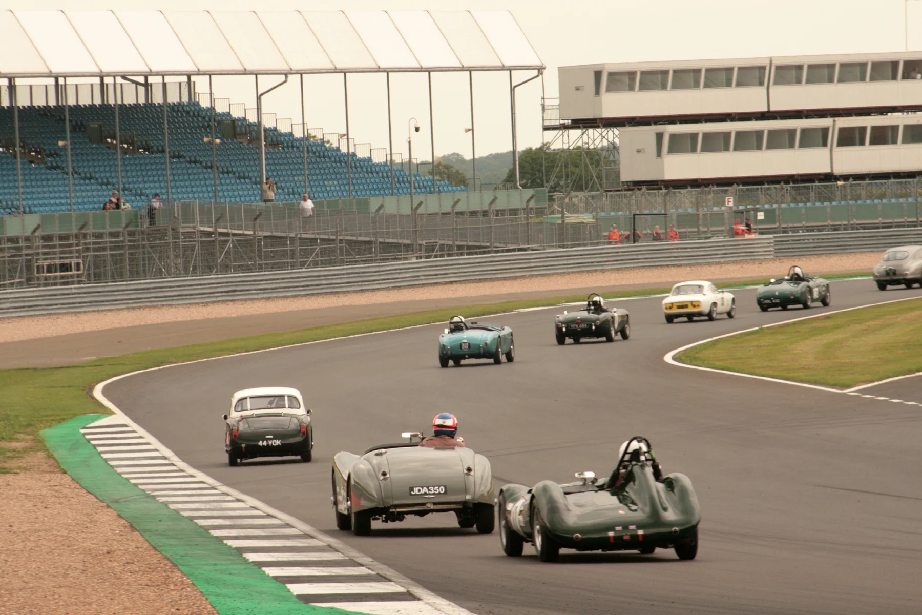 Glorious sight streaming through Woodcote - Tim Stamper with Aston DB2/4 going out of picture heads Jim Campbell, Robin Ellis, Tim Pearce, Adrian King, and now slightly detached Mark Hoble, John Harper & Alex Quattlebaum - see text above Photo - JT