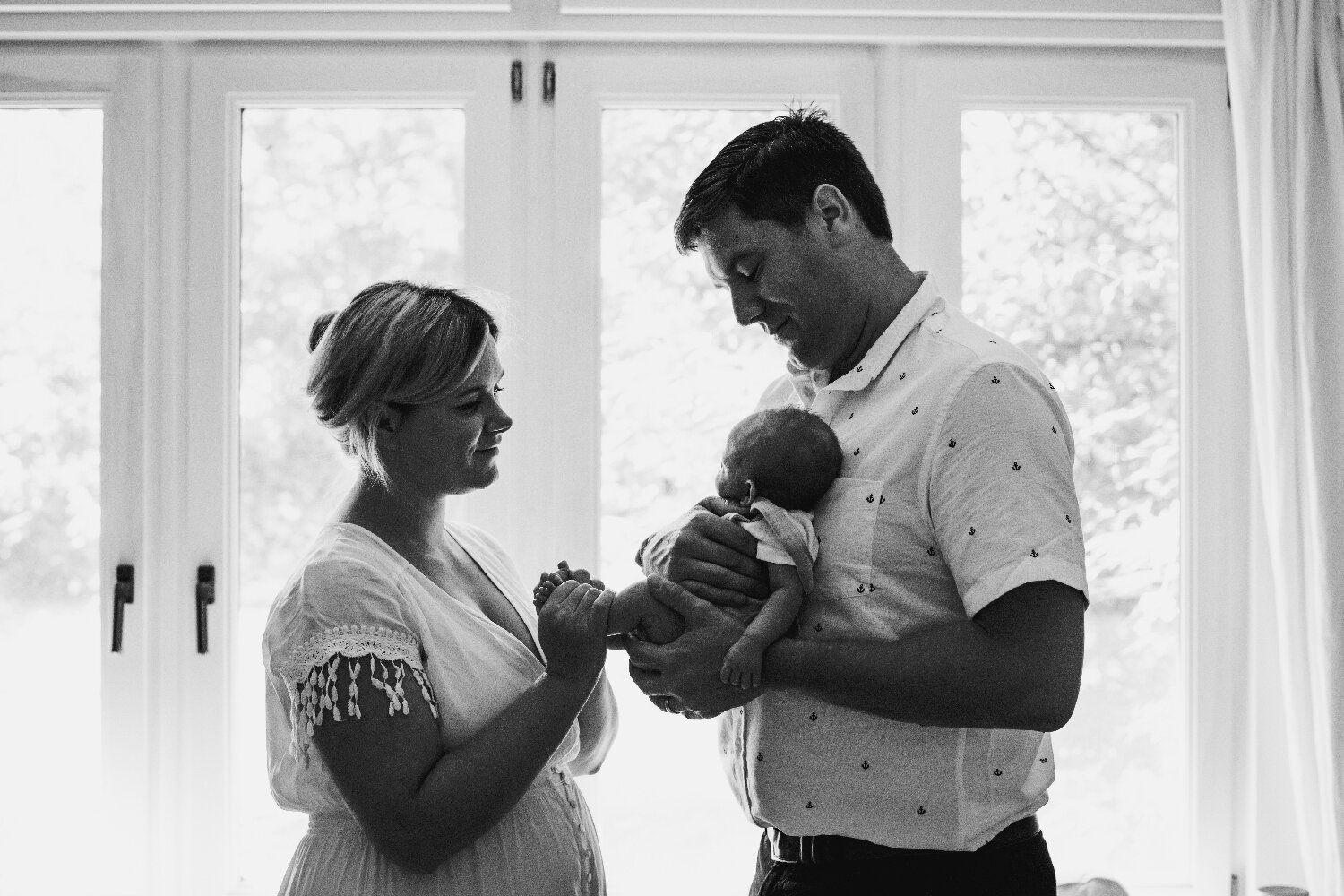 Backlit-Image-Of-Parents-Holding-Newborn