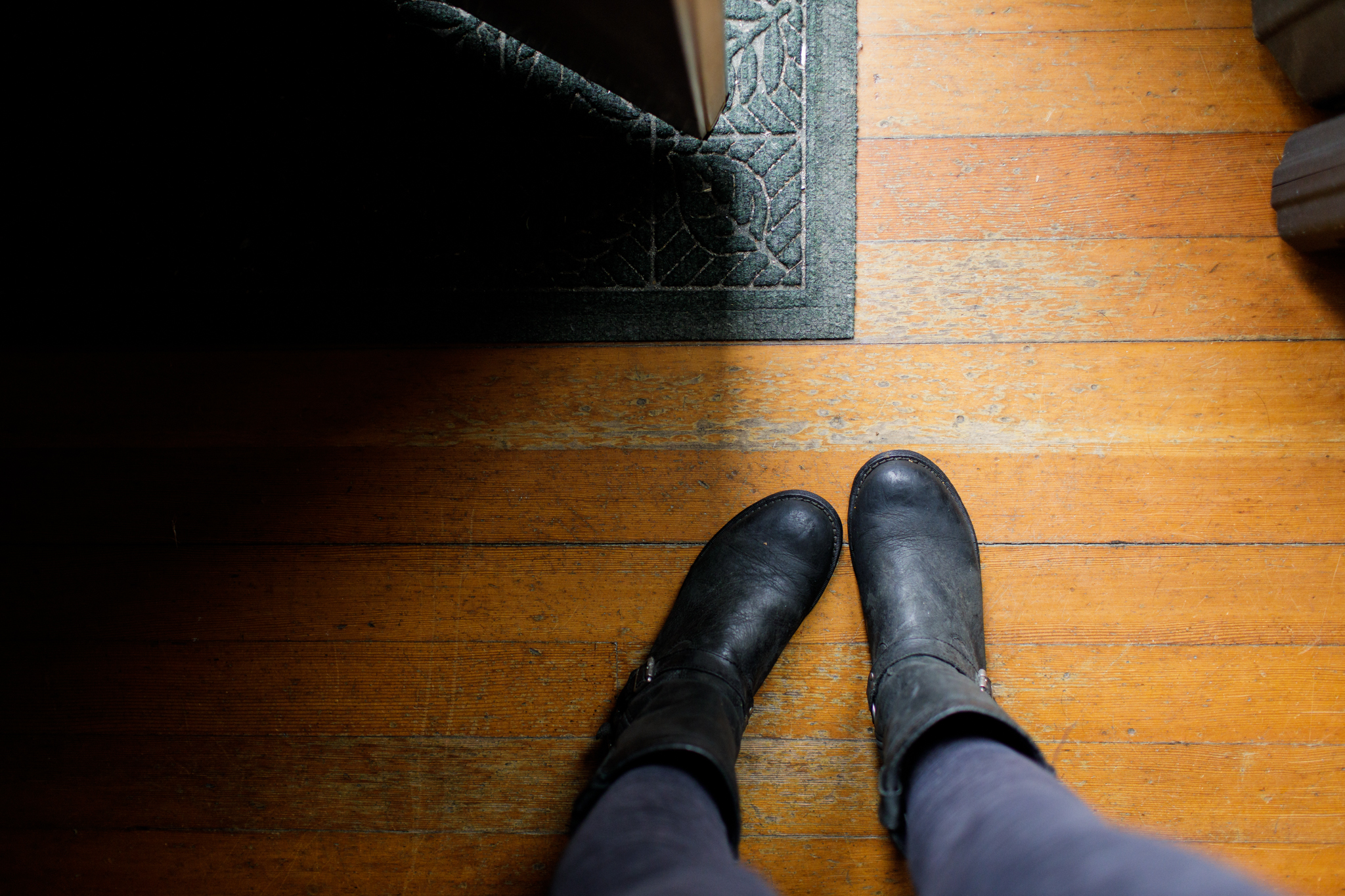 image of woman’s legs and boots, standing in a doorway, taken from above