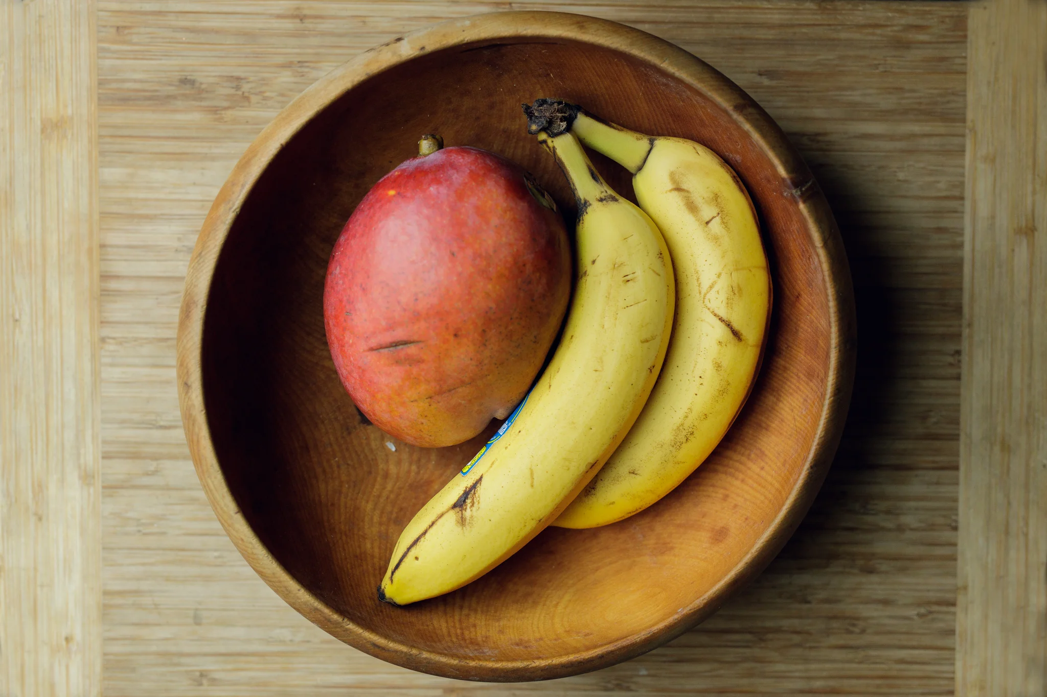 bananas and mango in a wooden bowl