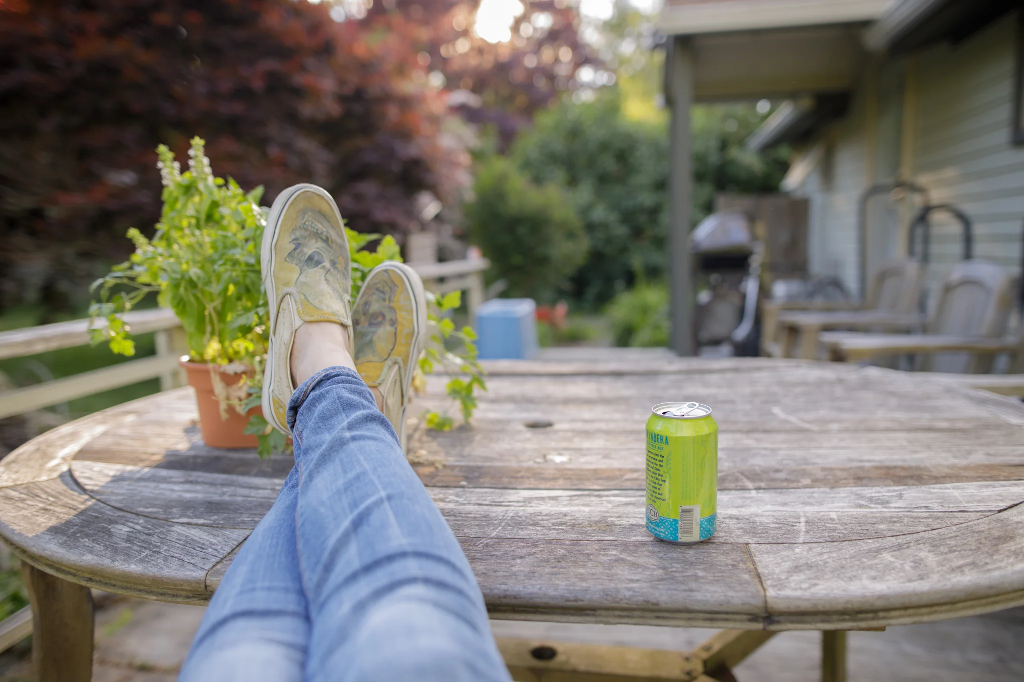 woman sitting at patio table with plant and beer
