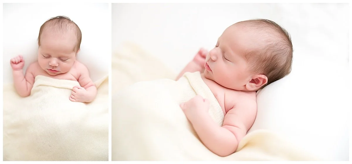 Newborn baby girl photographed on a white background lying under a cream colored background