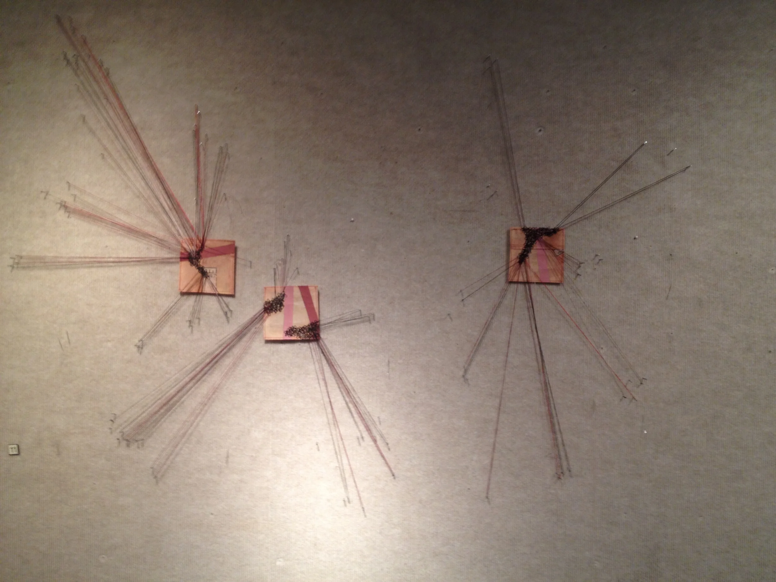 These are the same sewing pattern paper with eye closures attached. As I was thinking about this piece, I hoped that the thread would be again sewn through the eyes and extend beyond it's borders to a needle in the wall. I hoped the thread would pass through that needle and back to the paper. As I got started I realized the needle did not have enough body to give me the tension I needed, and my old eyes and not so nimble fingers couldn't work through all those needle heads. I went with #17 1 inch brads instead, and it worked great. I pinned the squares to the wall, but hoped with enough tension and thread, the squares would float above the wall. I really enjoyed working across the three. I'm torn on the outcome. I love the mass of thread in the 2-D pieces and really wanted to see that same amount of layering. At the same time, it felt like these needed to be in the process of growing towards those other shapes and too much thread wouldn't allow for that. But finally, there was only so much time and I still had other work to finish. This piece is a real beginning for me, and I can't wait to see where it goes. 