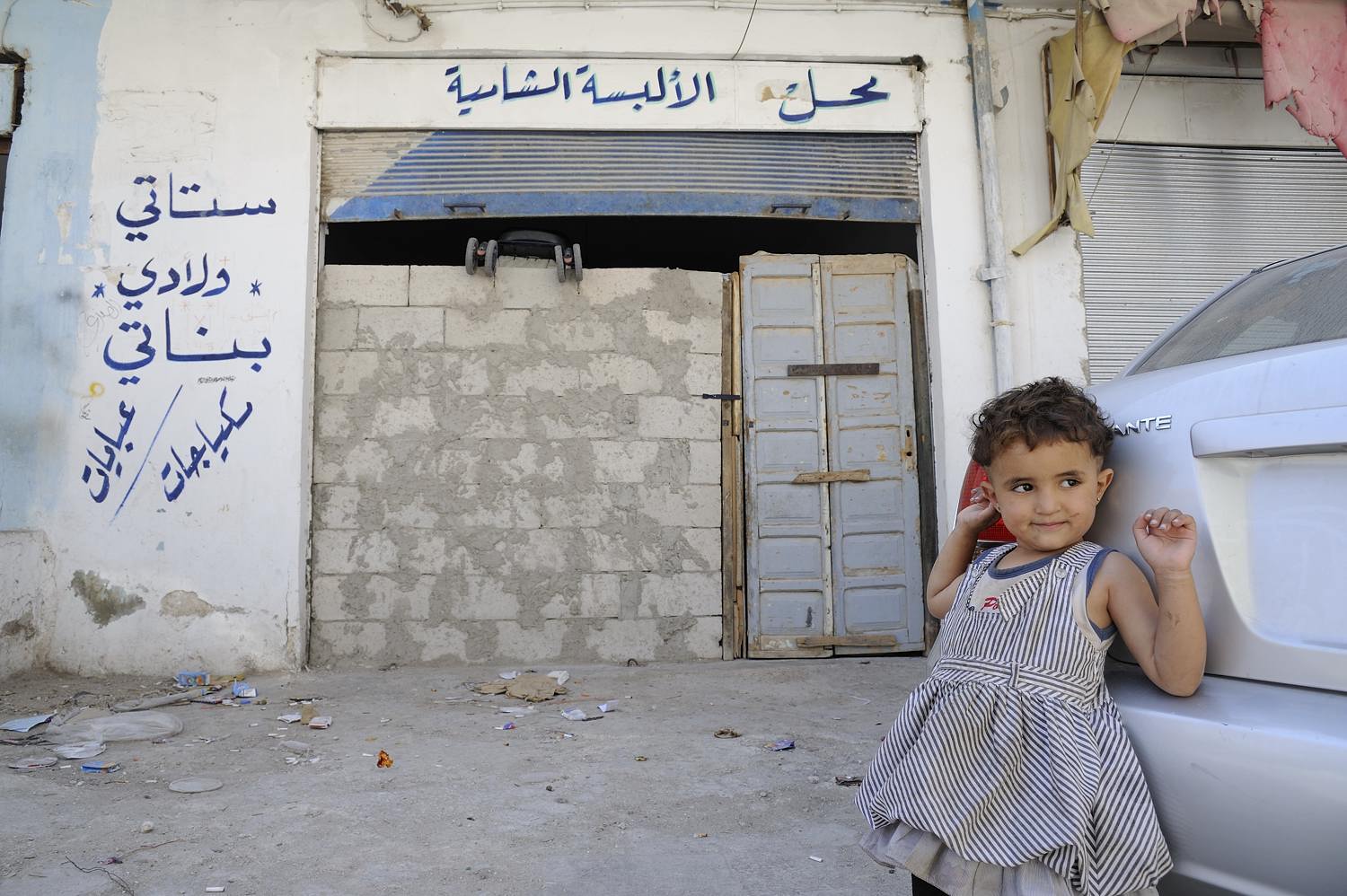  Amar (4) in front of the garage that she lives in together with her parents, grandmother, little brother and sister. Amar's father found a job picking fruit in Mafraq and is away all day.   Her mother has a hard time raising the children here, and s