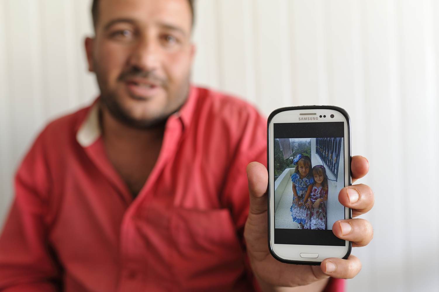  A father who lost 4 children during a bombardment shows an image of his two daughters. 