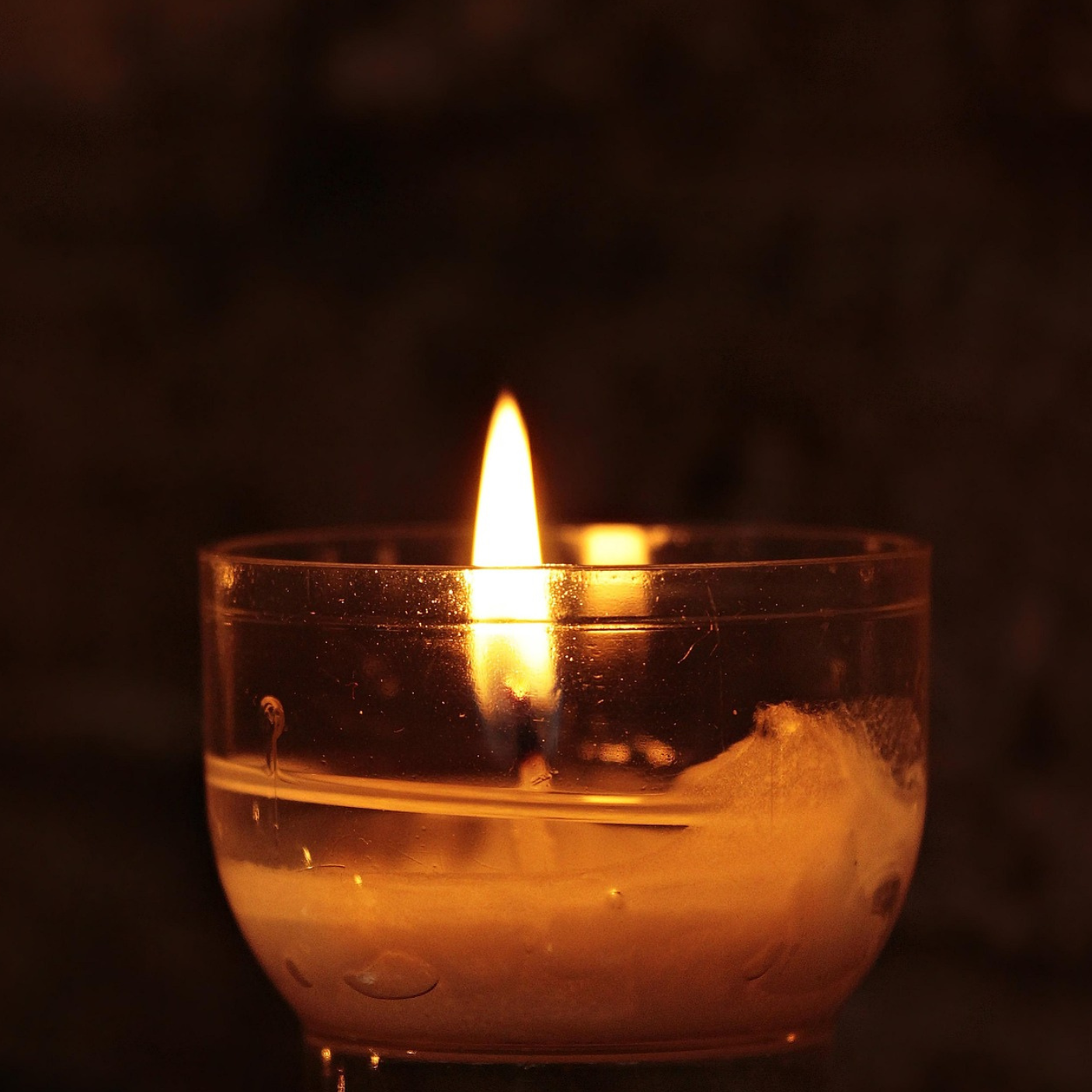 Single candle glowing in a dark room, a quiet symbol of hope and resilience in grief