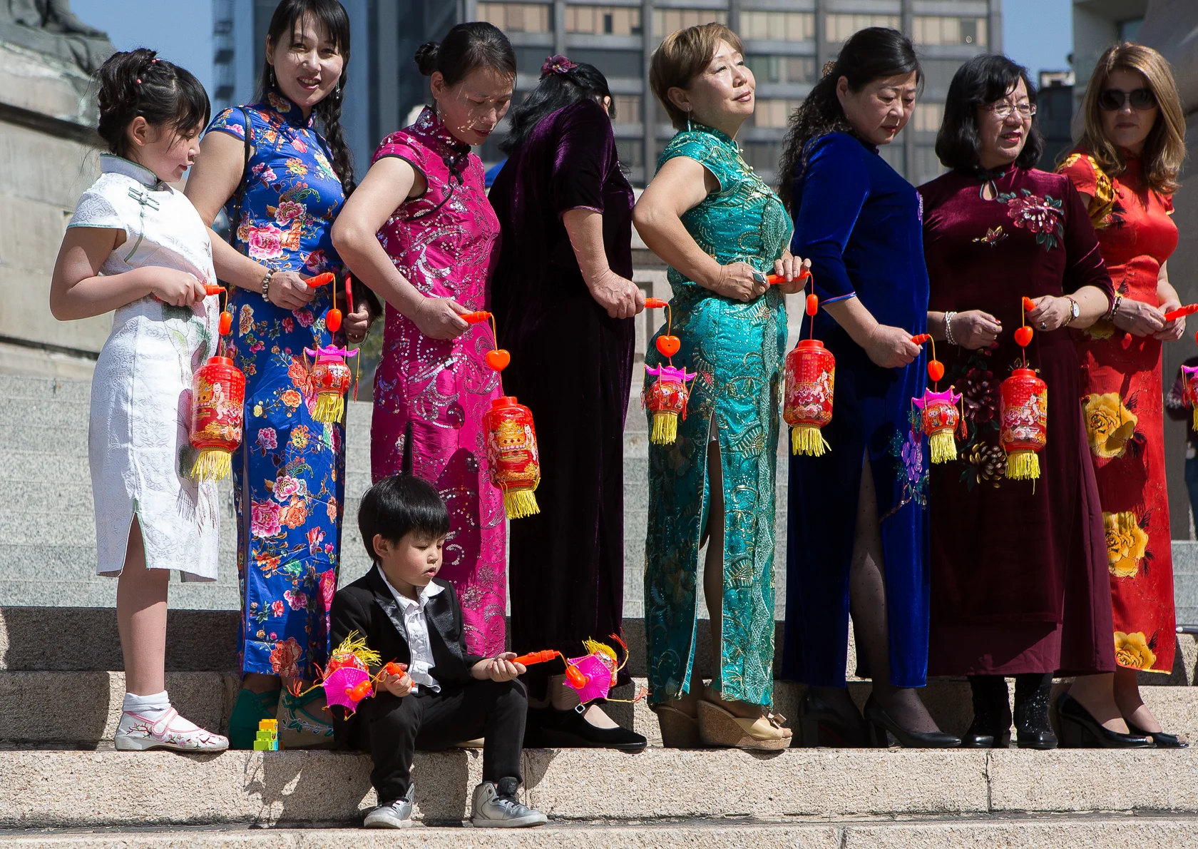 A boy plays with the toys in his hand as the ladies pose for their photograph on the steps of the Angel de la Independecia (Angel of Independence) in Mexico City, Mexico