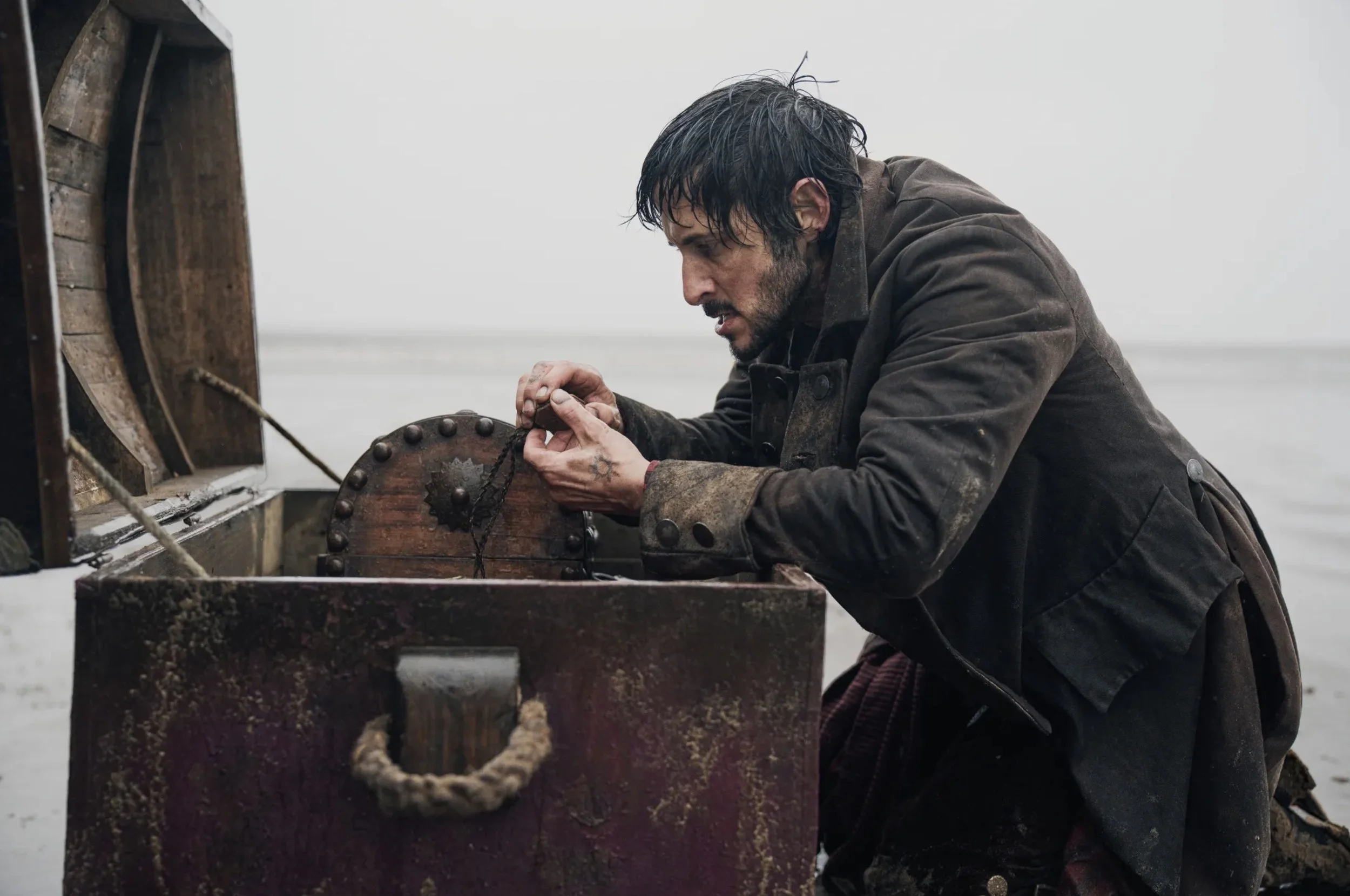 David Oyelowo as Long John Silver examining a battered treasure chest in Treasure Island