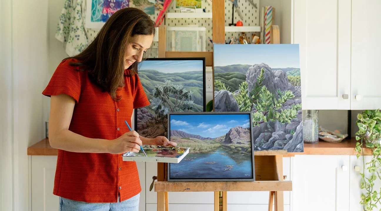 Fine artist Kristen Walker in her Santa Barbara studio with original acrylic paintings of Santa Cruz Island, showcasing California native landscapes and conservation-inspired artwork.