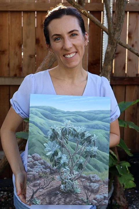 Artist Kristen Walker holding a painting of a Channel Islands Hazardia plant