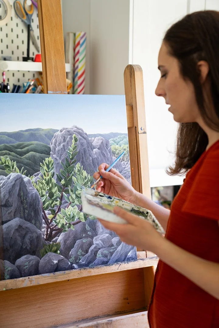 Over-the-shoulder view of artist Kristen Walker painting an Island Manzanita on Santa Cruz Island. Original acrylic artwork inspired by California's native plants and Channel Islands conservation.