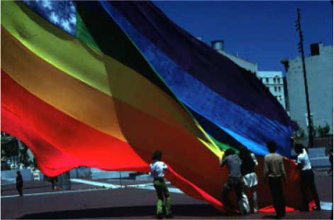 The Original 8-color Rainbow Flag, San Francisco United Nations Plaza, June 25, 1978. Photo: James McNamara. Courtesy of the artist. Baker is third from the left "in satin pajamas with my long hair." 