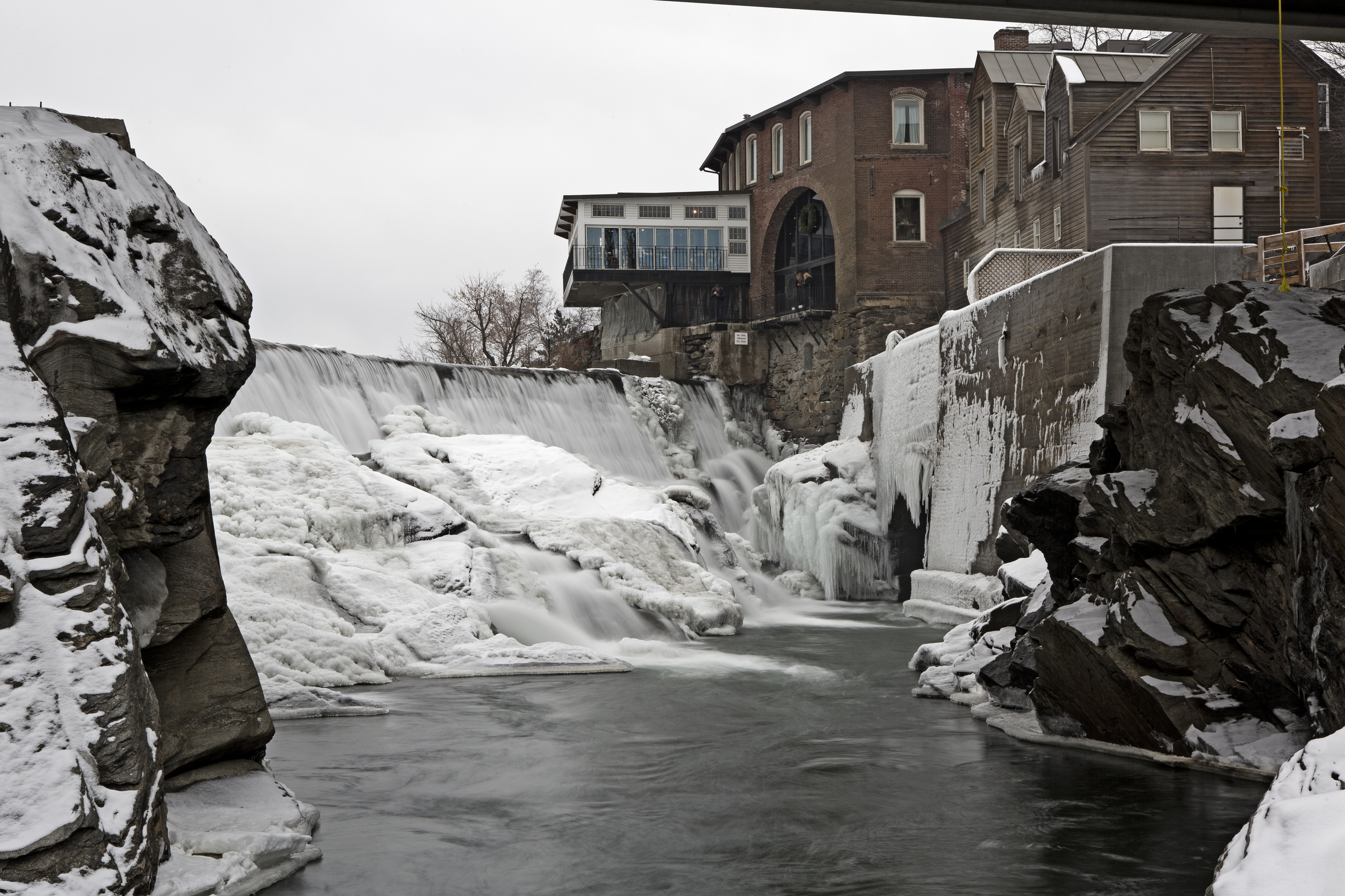 the ottauquechee river flows past the old mill building that houses simon pearce glass studio, restaraunt, and show room.