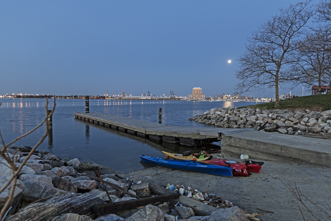 A full moon over the harbor at twilight and avoiding the trash at the city boat launch.