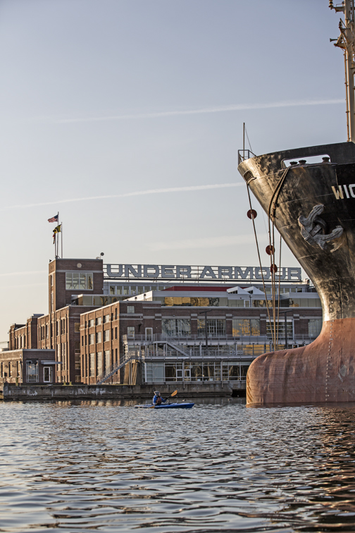 Sloane paddling past UA and a boat loaded with sugar of some sort at the dock of Domino.