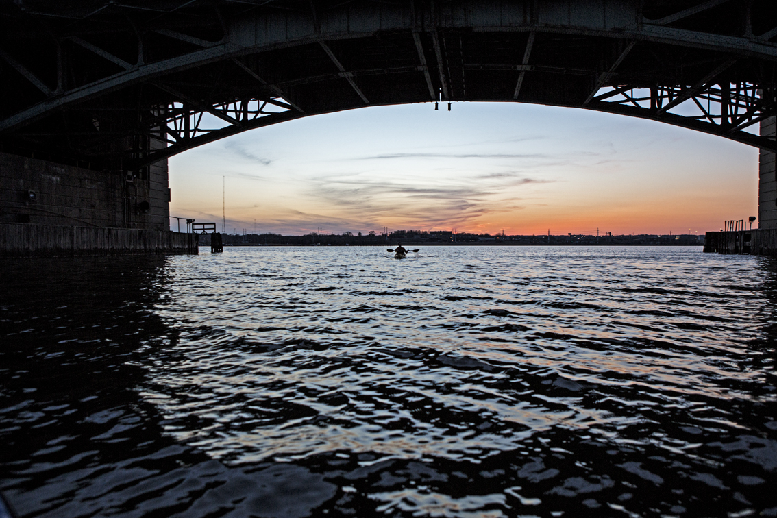 Sunset on the harbor through the archway of a bridge.