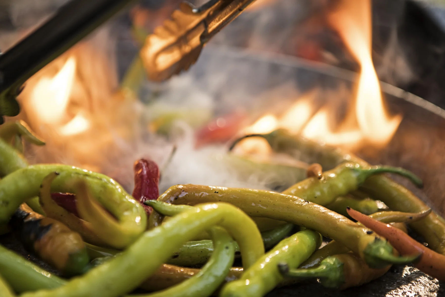Cowboy cooking peppers over open flame.