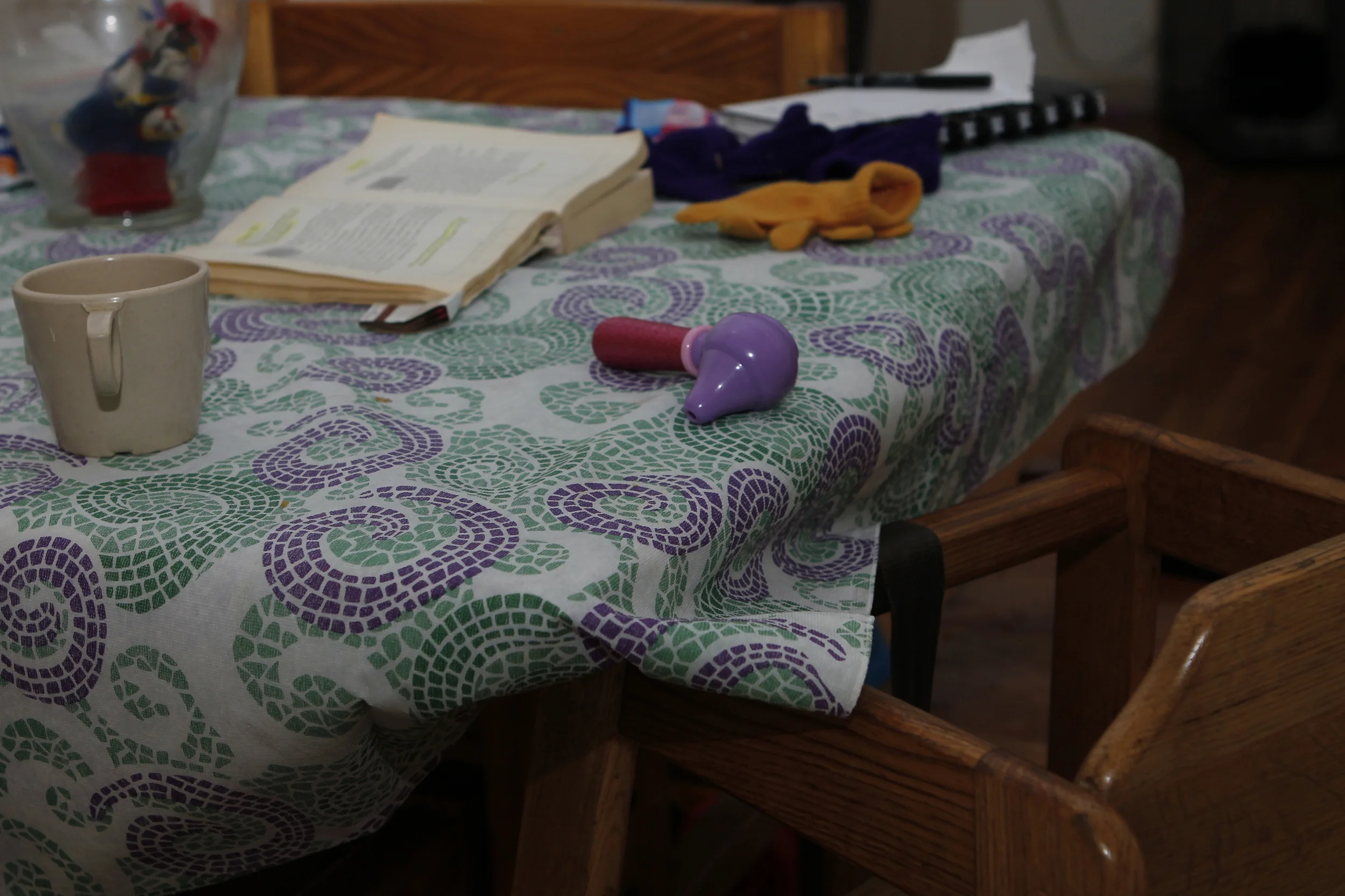 a kitchen table, with a book for a Mother and a booster seat and toy for her son.jpg