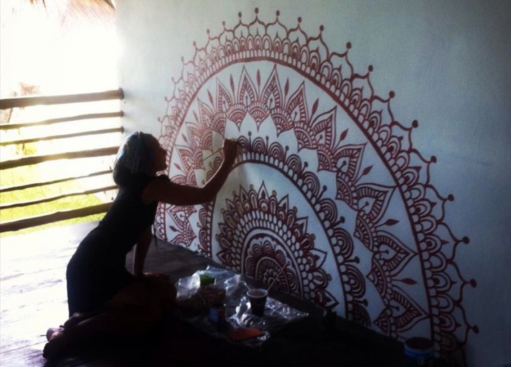 Darcy paints a mehndi inspired mural on the yoga studio wall at Utopia, Tulum. 