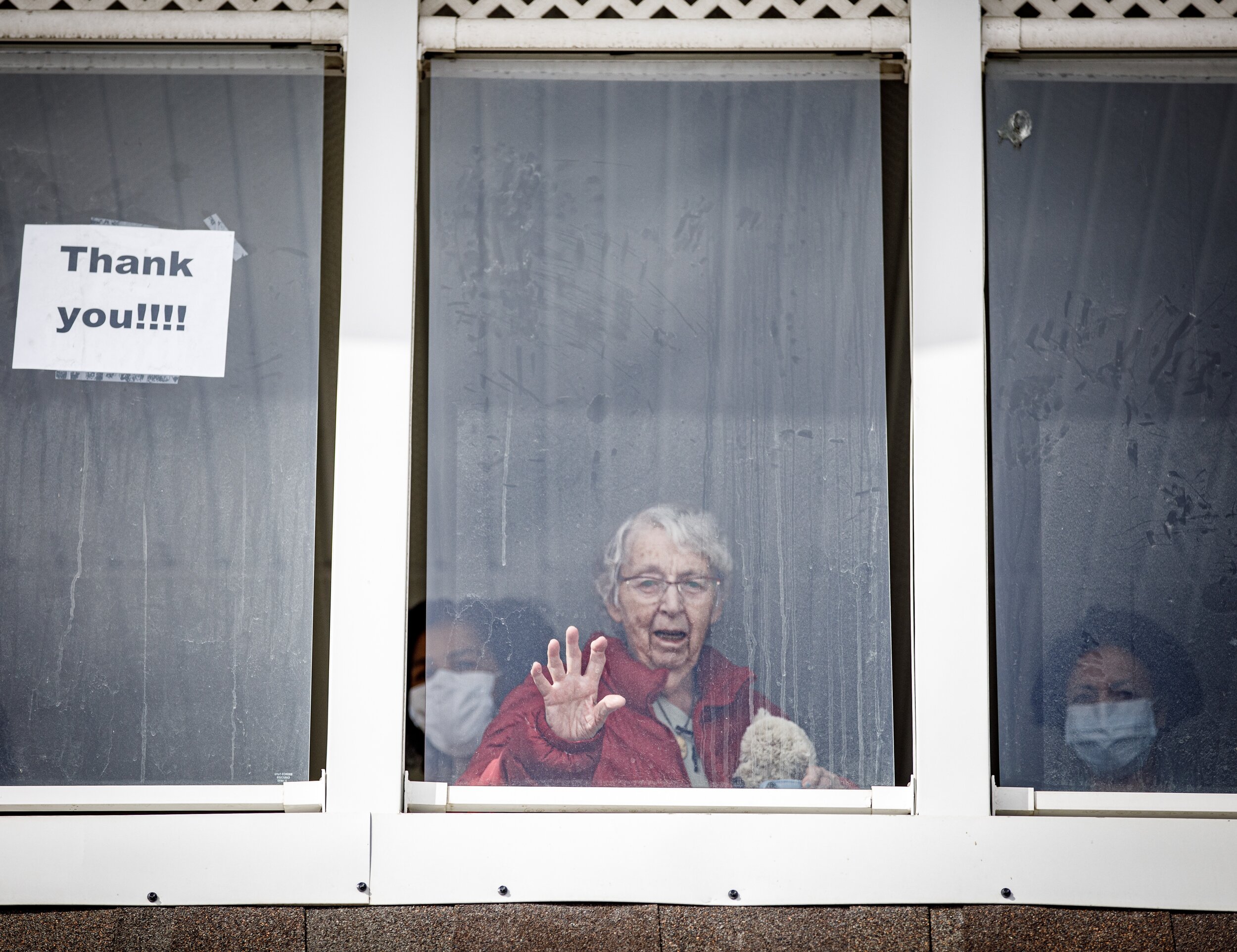  A resident at a continuing care centre waves to family and the community who came out to support seniors and staff dealing with the COVID-19 quarantine on April 1, 2020, in Calgary, Alberta. 