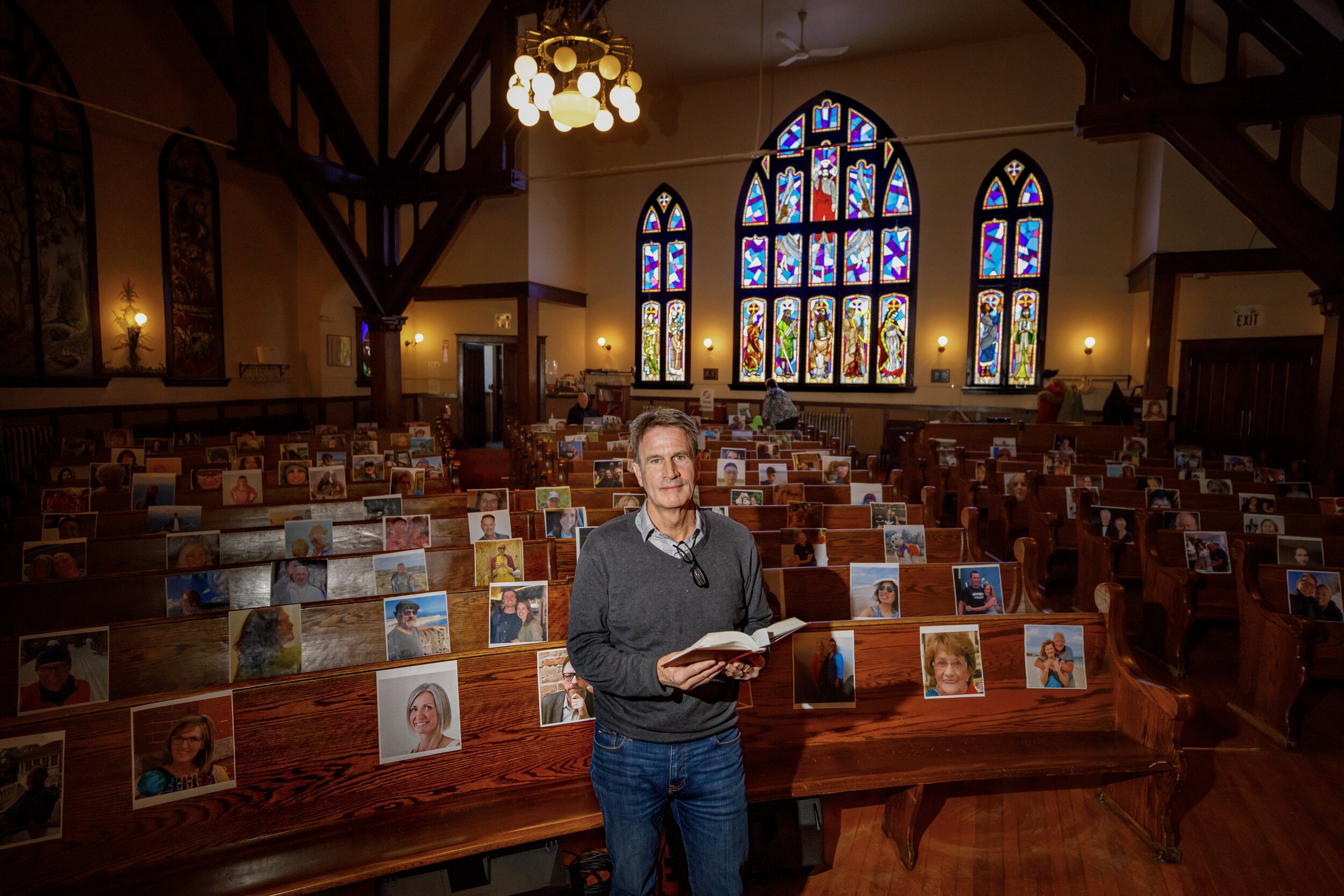  Rev. Jon Pentland, minister of Hillhurst United Church in Calgary, Alberta, with photos of community members on the pews after they started online only church services because of the COVID-19 pandemic. 