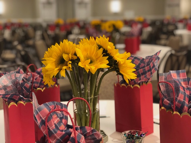 Kelly Plosker worked her magic in the ballroom and carried the “Fully Alive” theme with bursts of color as seen in these sunflowers and red goodie bags.
