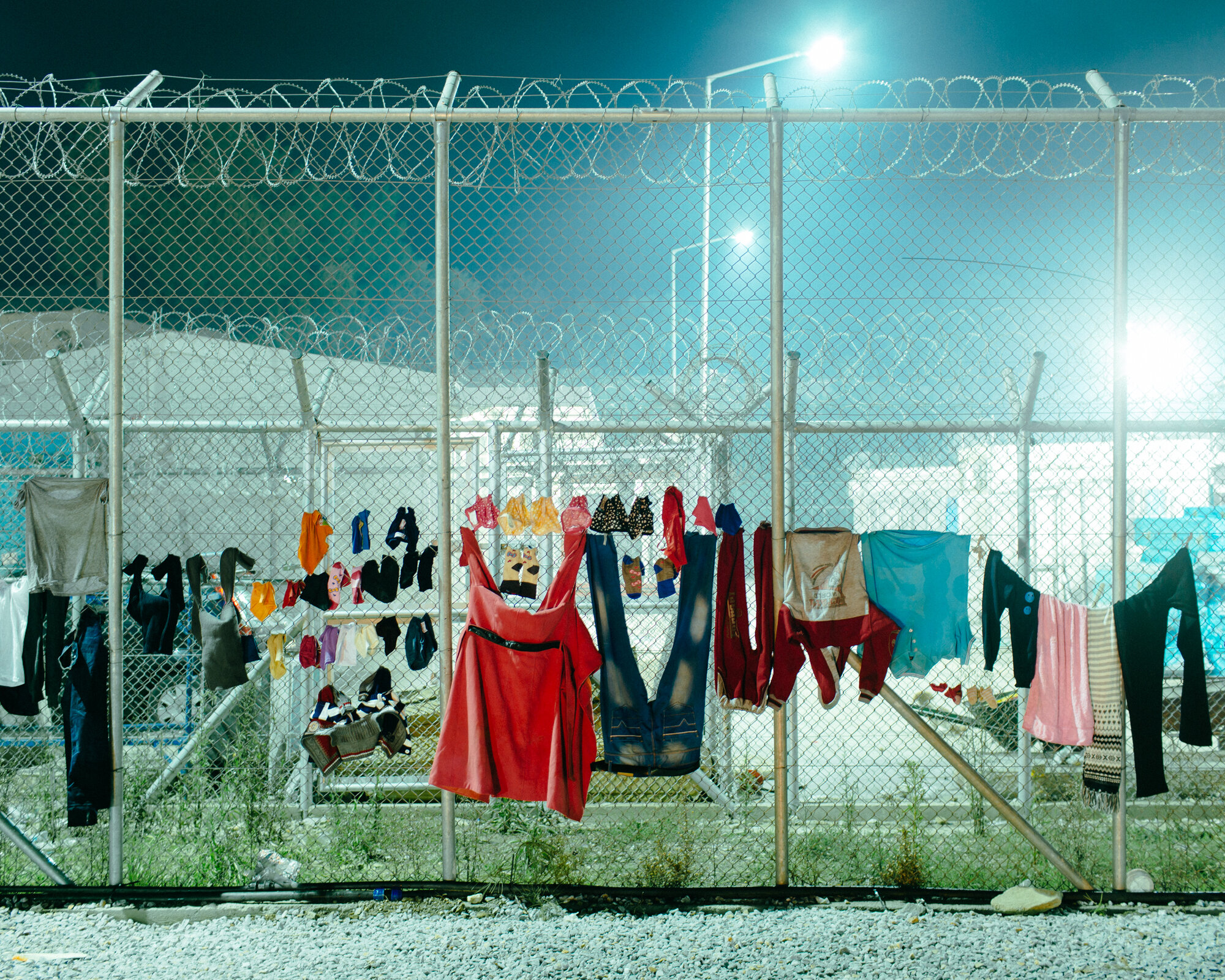  Clothes presumably hung to dry on the formidable fences that cordon off the administration area inside Moria, soak in the night’s rain. 