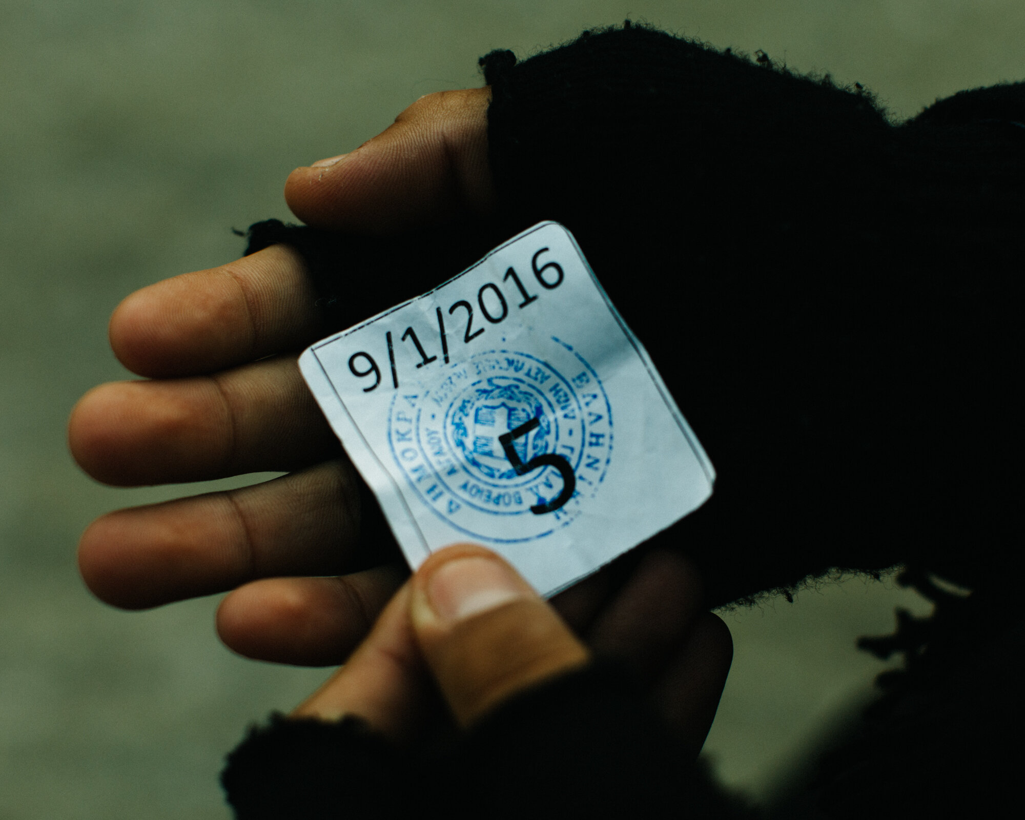  Ammar holds his numbered ticket that he received upon entrance into Moria, Mytilene’s refugee camp and registration center. Once his number is called, he must wait in line, sometimes for a full day, to receive his EU registration papers. 