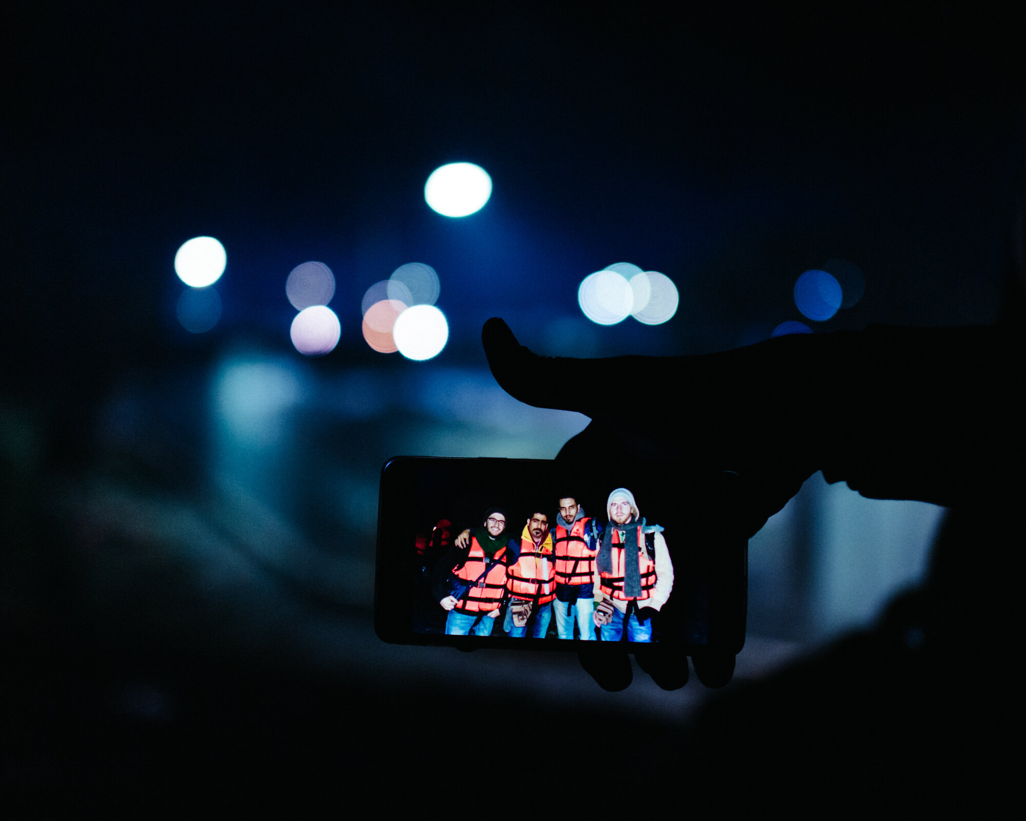  In the refugee camp, Moria, a Syrian man shows a photo of he and his friends smiling nervously as they are about to embark across the Aegean Sea from the Turkish side in the early hours of the morning. 