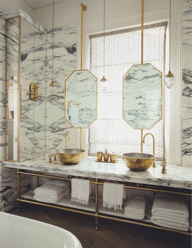 The combination of the Arabescato marble and the unlacquered brass provides plenty of glamour and drama in this master ensuite. ( Maddux Creative - photograph by Ricardo Labougle)