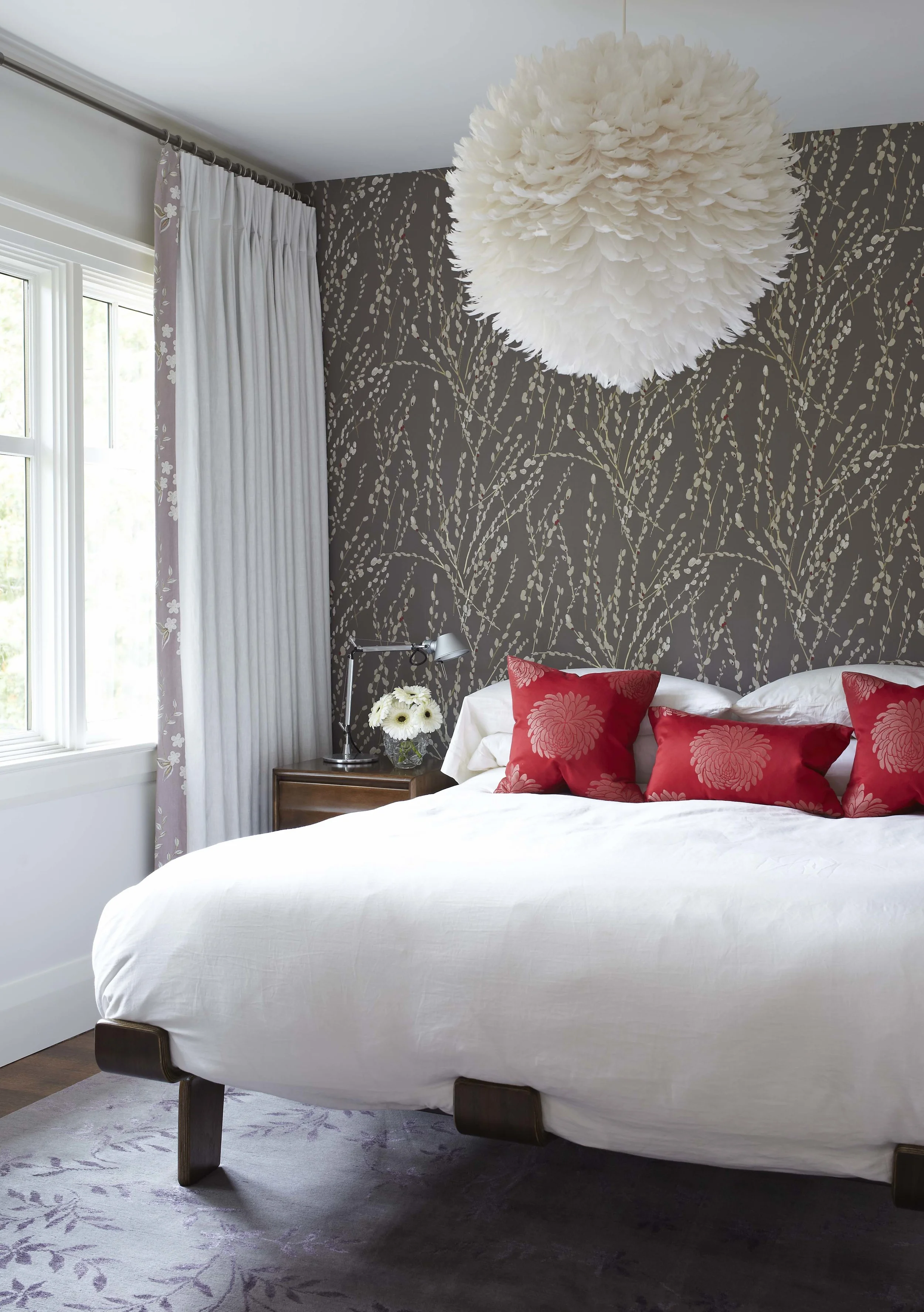 This bed, inspired by the Case House Study projects in Los Angeles - experiments in residential architecture from the 1950's, and the textured lighting fixture, bold colour from some throw pillows and a floral grey wallpaper make this contemporary bedroom inviting, while also acting as a place of serenity for our clients (Casey Design / Planning Group Inc.- photograph by Michael Graydon)